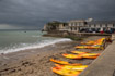 Bright orange canoes line up along the beach before a storm on the Isle of Wight