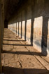 Evening light casts strong shadows from vertical posts in the outer galleries of Angkor Wat