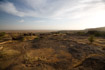 A stark, burned landscape of bare sandstone and dry scrub forms the edge of the Bandiagara escarpment in Mali.